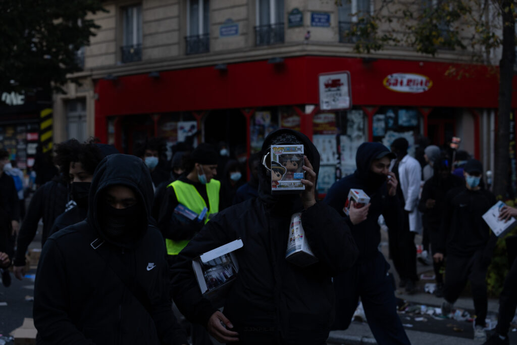 Vermummte Personen tragen bei den Ausschreitungen in Paris am 17. Oktober 2026 geplünderte Waren